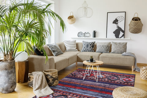 Living room with a beige sectional sofa, decorative pillows, a coffee table, and a colorful rug.